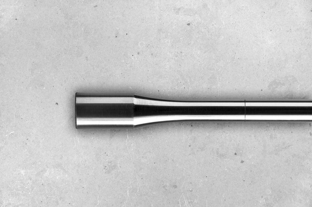 Detalle de una probeta de fatiga sobre una superficie de cemento